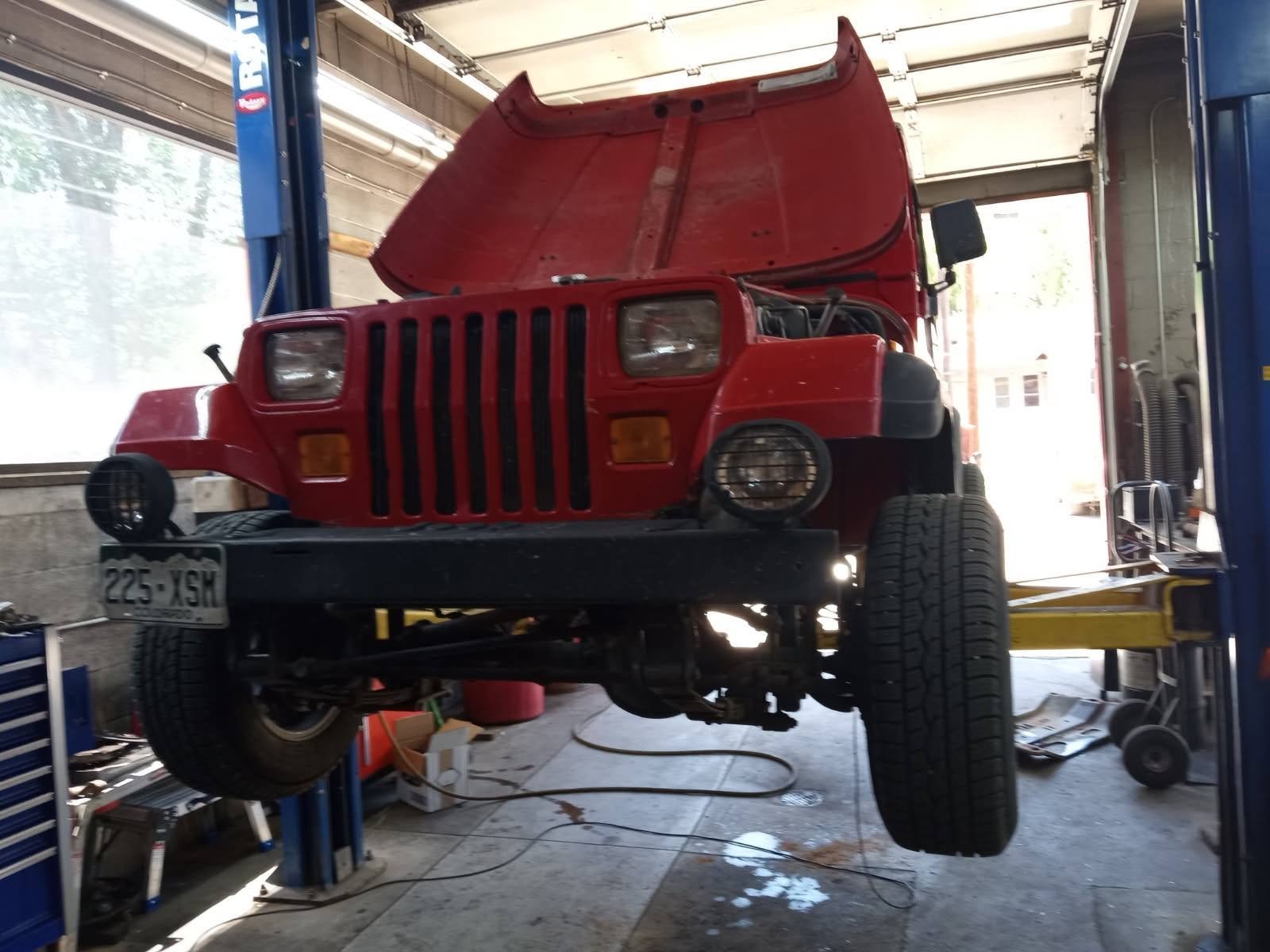 Red Jeep on the lift for suspension work